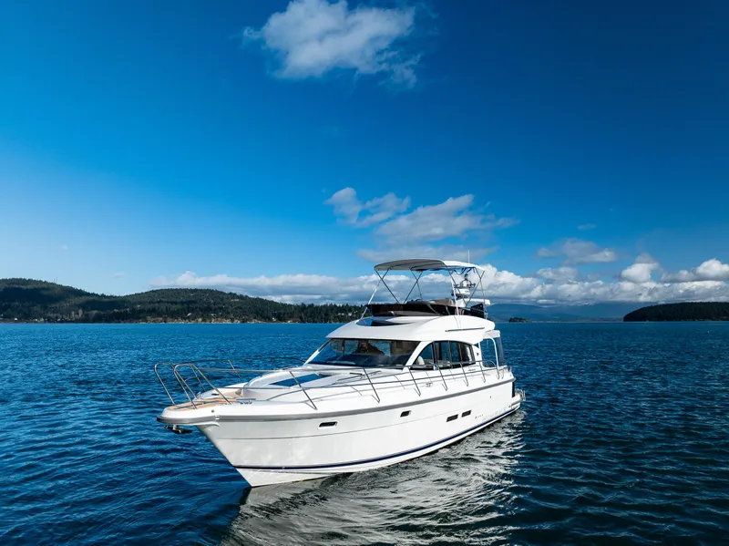 Slide: The Image of 2024 Nimbus 405 Flybridge yacht cruising on a serene blue lake under a clear sky. - 37