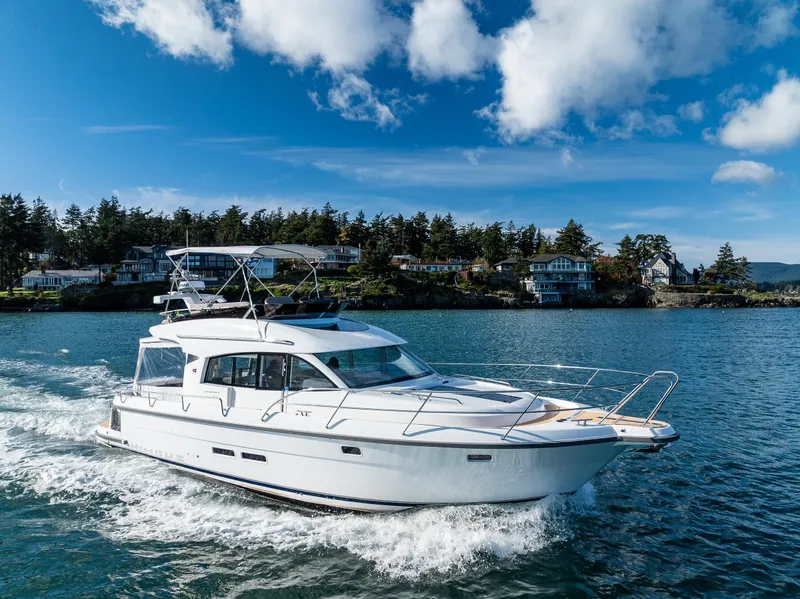 Slide: The Image of 2024 Nimbus 405 Flybridge cruising on a scenic lake under a clear blue sky. - 42