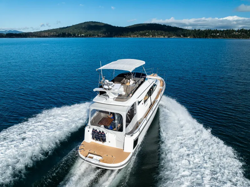 Slide: The Image of Nimbus 405 Flybridge 2024 cruising on a serene lake with scenic mountain backdrop. - 44