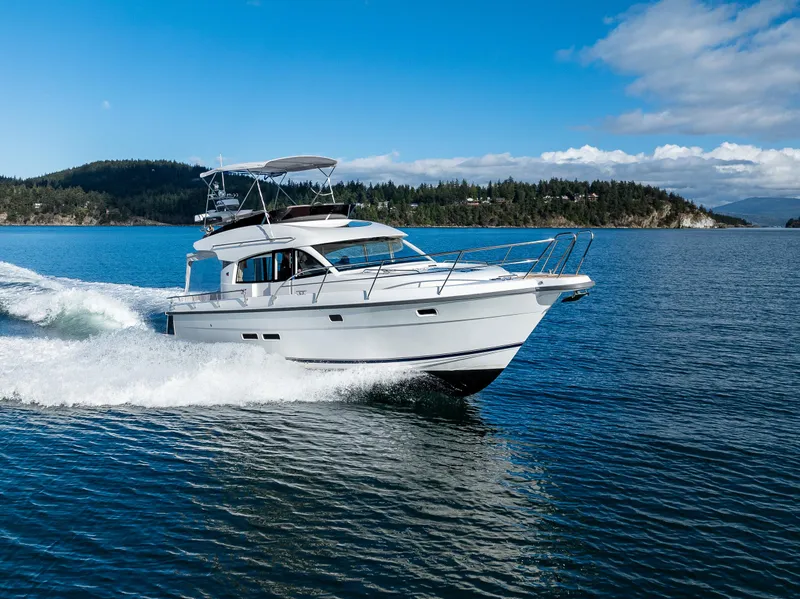 Slide: The Image of 2024 Nimbus 405 Flybridge cruising on a scenic lake under a clear blue sky. - 49