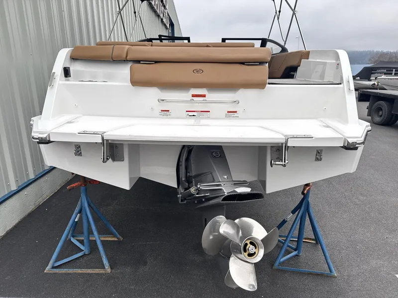Slide: The Image of 2025 Cobalt CS23 boat on stands, rear view with propeller and tan seating. - 5
