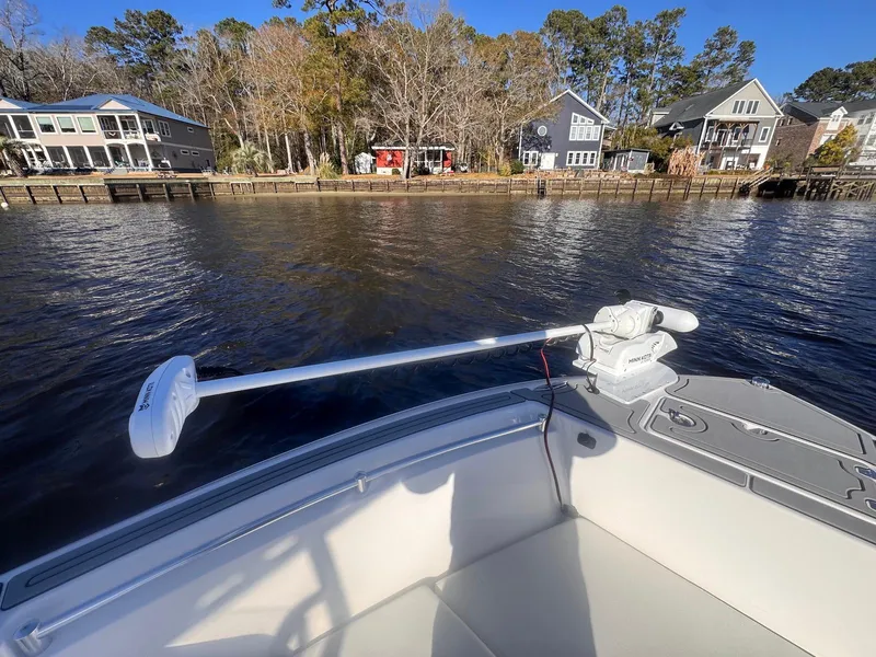 Slide: The Image of 2024 Aquasport 2200 Center Console boat on a calm lake near waterfront homes. - 11