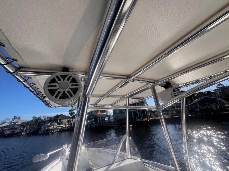 Slide: The Image of 2024 Aquasport 2200 Center Console boat with T-top and speakers on a sunny day. - 24