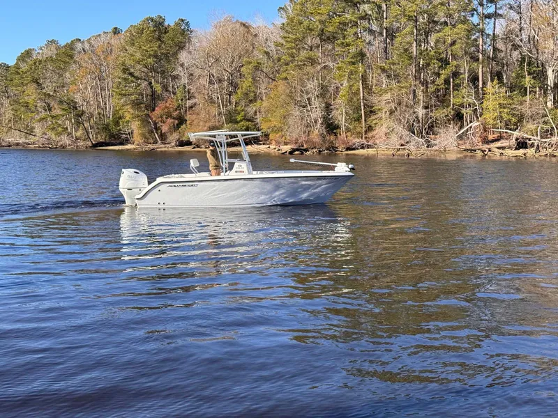 Slide: The Image of 2024 Aquasport 2200 Center Console boat cruising on a serene lake. - 5