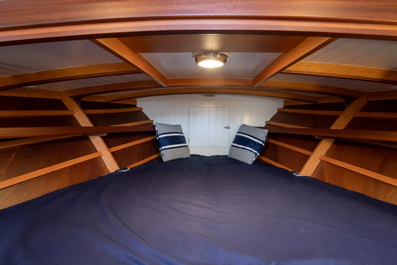 Slide: The Image of Cozy cabin interior of 2021 Brooklin Boat Yard 32 Express with wooden shelves and striped pillows. - 14