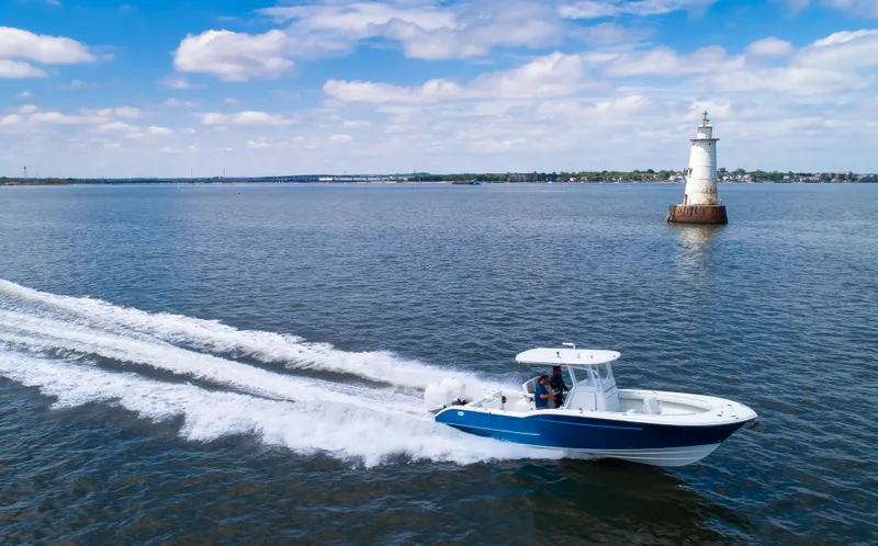 Slide: The Image of 2025 Buddy Davis 28 Center Console boat cruising near a lighthouse on a sunny day. - 13
