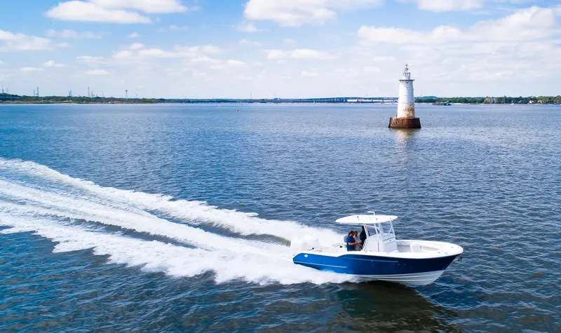 Slide: The Image of 2025 Buddy Davis 28 Center Console boat cruising near a lighthouse on open water. - 15