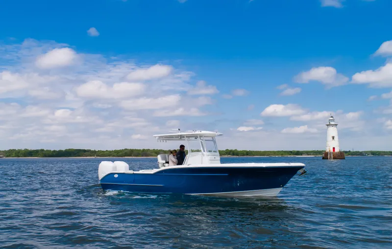 Slide: The Image of 2025 Buddy Davis 28 Center Console boat cruising near a lighthouse on a sunny day. - 3