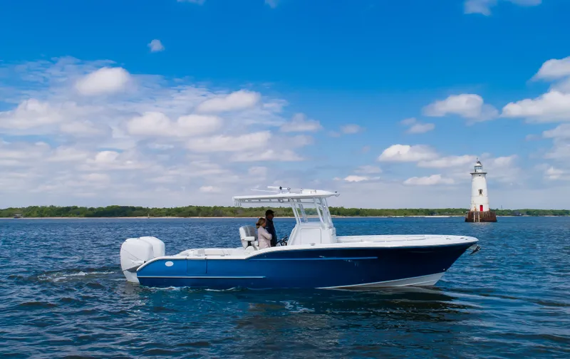 Slide: The Image of 2025 Buddy Davis 28 Center Console boat cruising near a lighthouse on a sunny day. - 4