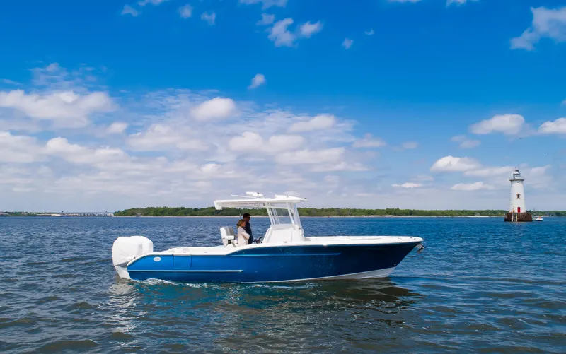 Slide: The Image of 2025 Buddy Davis 28 Center Console boat cruising near a lighthouse on a sunny day. - 6