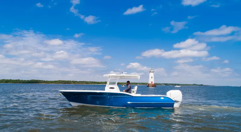 Slide: The Image of 2025 Buddy Davis 28 Center Console boat cruising near a lighthouse on a sunny day. - 8