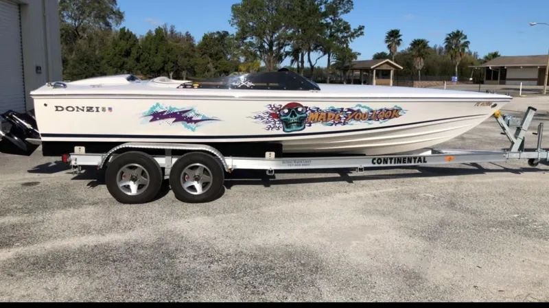 Slide: The Image of 2018 Donzi 22 Classic speedboat on trailer with vibrant graphics, parked outdoors. - 23