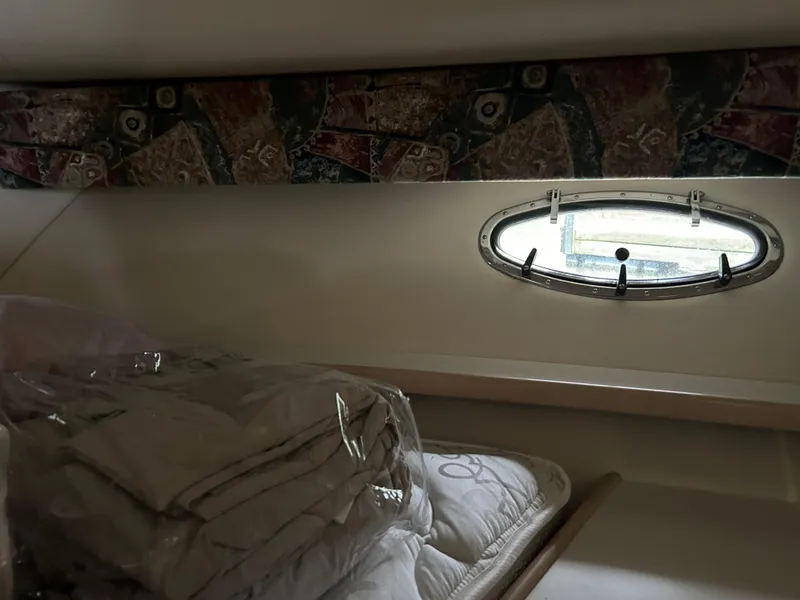 Slide: The Image of 1997 Tiara Yachts 3500 Express cabin interior with bedding and porthole window. - 32
