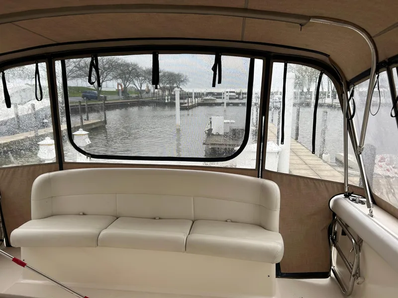 Slide: The Image of 1997 Tiara Yachts 3500 Express interior with white seating, overlooking marina dock. - 42