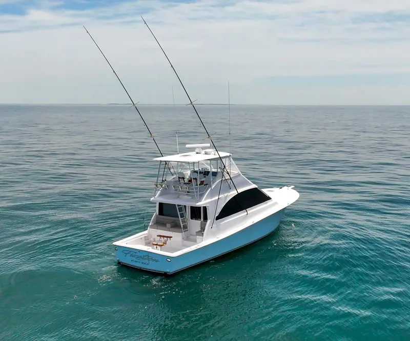 Slide: The Image of 2001 Ocean 52 Convertible yacht on open sea, clear sky, fishing rods visible. - 2