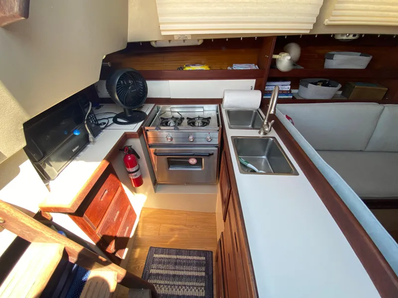 Slide: The Image of 1988 Catalina 30 yacht interior kitchen with stove, sink, and wooden cabinetry. - 14