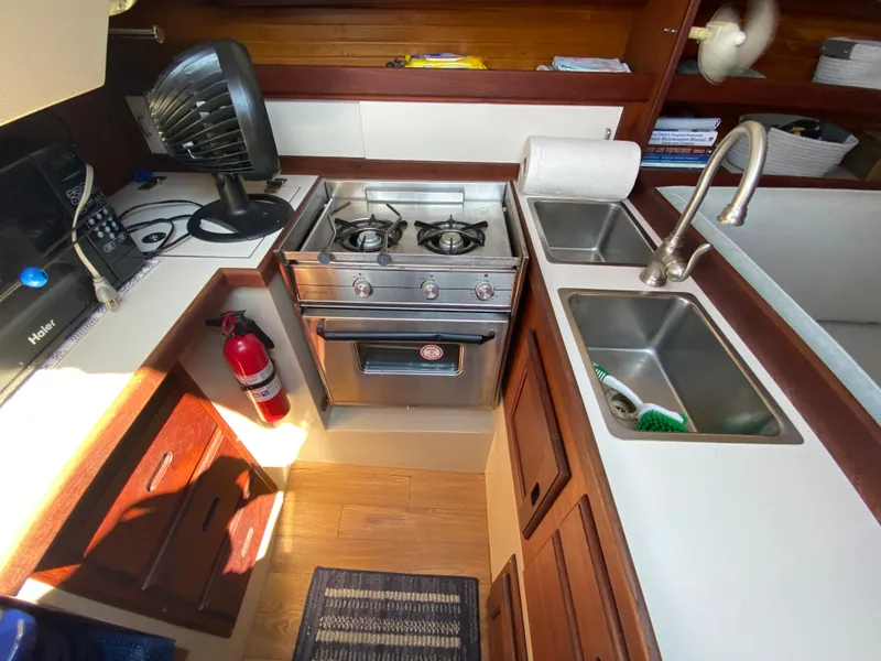 Slide: The Image of 1988 Catalina 30 yacht kitchen with stove, sink, and storage. - 17
