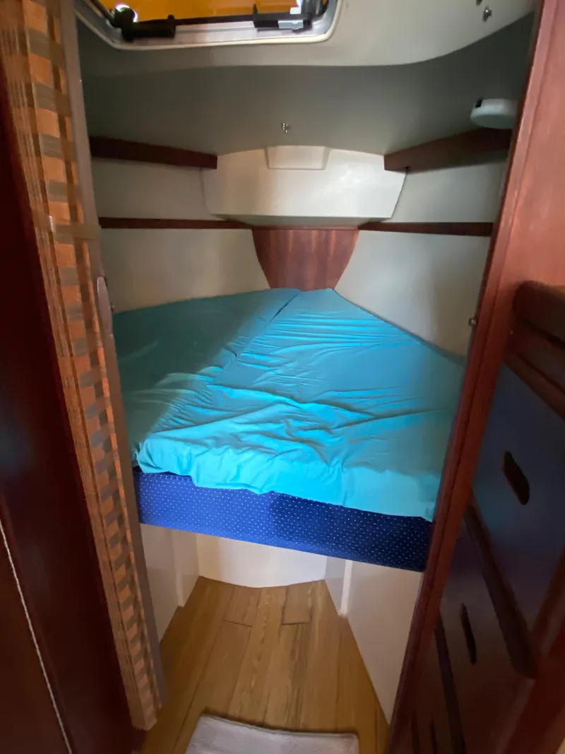 Slide: The Image of 1988 Catalina 30 sailboat cabin with blue bedding and wooden interior. - 24
