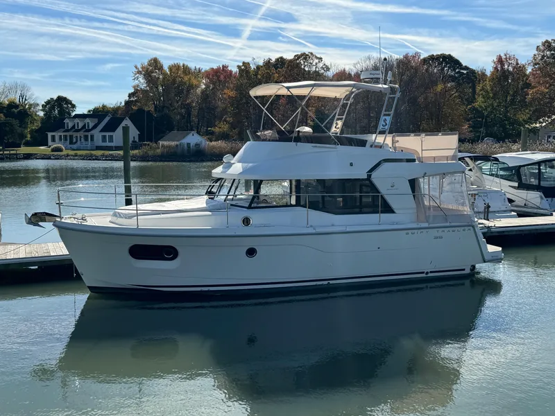 Slide: The Image of 2023 Beneteau Swift Trawler 35 docked on a serene lake with autumn trees. - 0