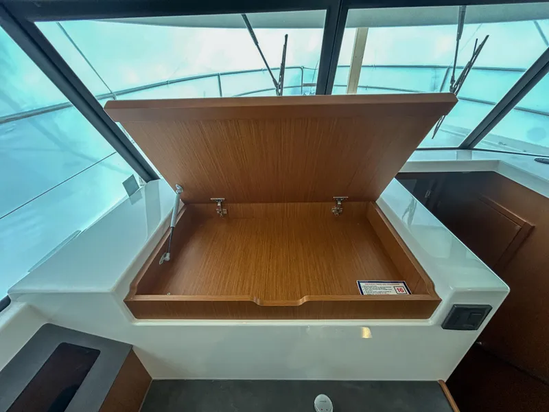 Slide: The Image of 2023 Beneteau Swift Trawler 35 interior storage compartment with open wooden lid. - 16