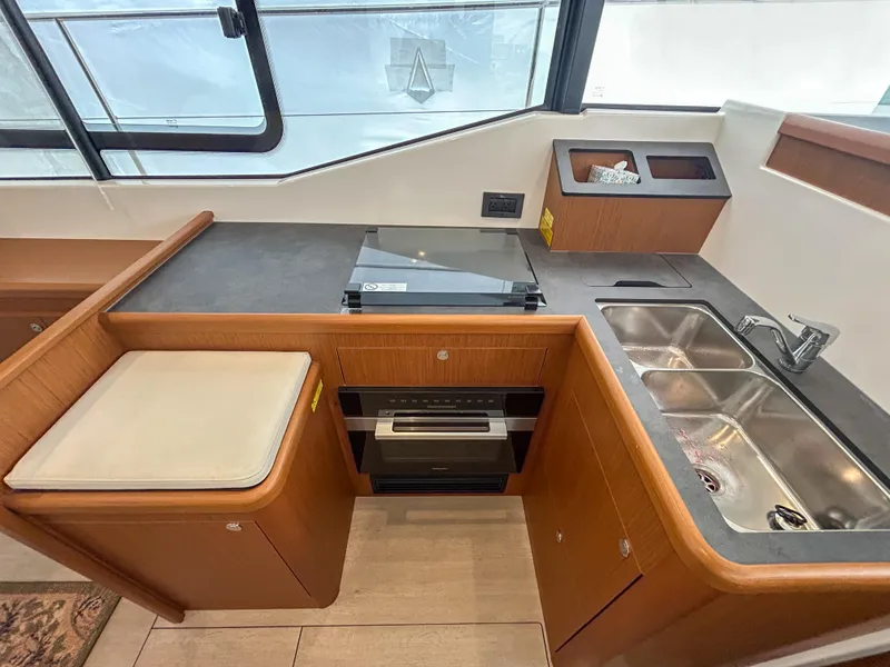 Slide: The Image of Modern kitchen in 2023 Beneteau Swift Trawler 35 with stove, sink, and wood cabinetry. - 17