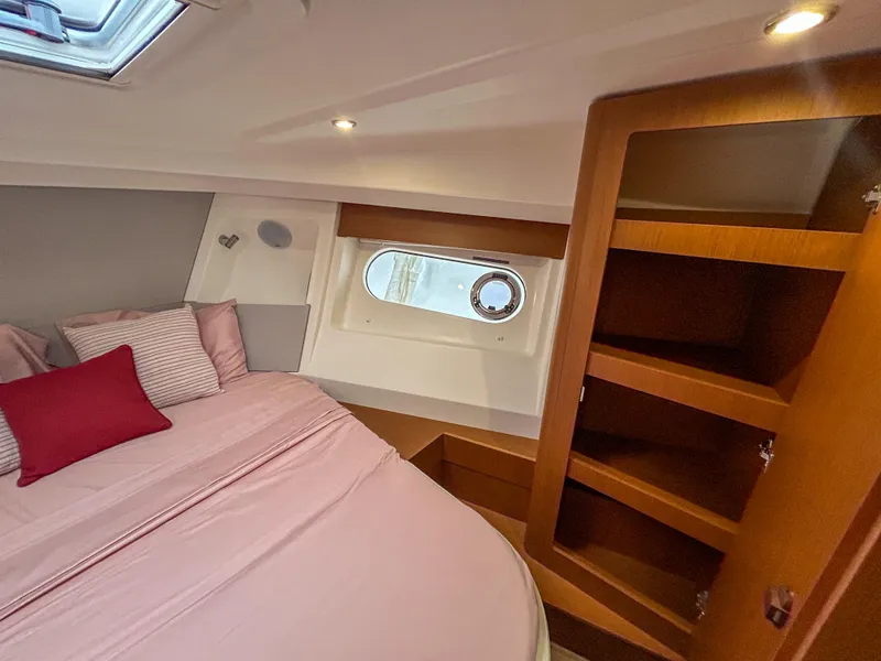 Slide: The Image of Cozy bedroom interior of 2023 Beneteau Swift Trawler 35 with wooden shelves and porthole window. - 22