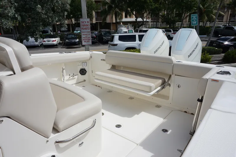 Slide: The Image of 2026 Boston Whaler 330 Outrage interior with seating and Mercury engines in a parking lot. - 11