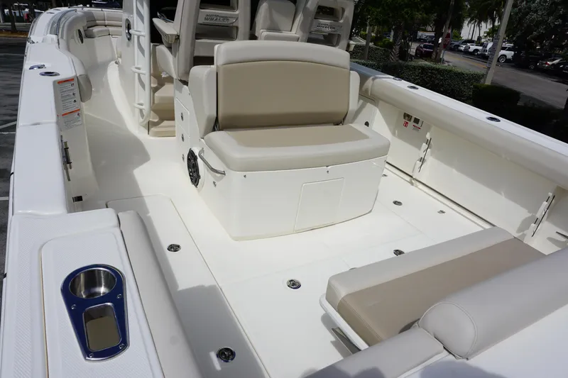 Slide: The Image of 2026 Boston Whaler 330 Outrage boat interior with beige seating and cup holders. - 12