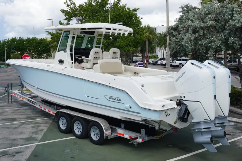 Slide: The Image of 2026 Boston Whaler 330 Outrage boat on trailer, featuring dual Mercury engines. - 2