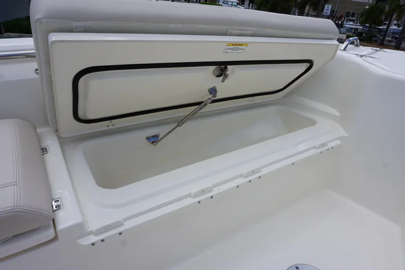 Slide: The Image of 2026 Boston Whaler 280 Dauntless storage compartment with open lid and cushioned seating. - 37