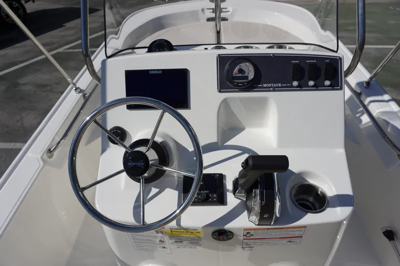 Slide: The Image of 2025 Boston Whaler 150 Montauk boat console with steering wheel and controls. - 19