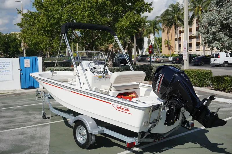 Slide: The Image of 2025 Boston Whaler 150 Montauk boat on trailer, parked outdoors. - 2
