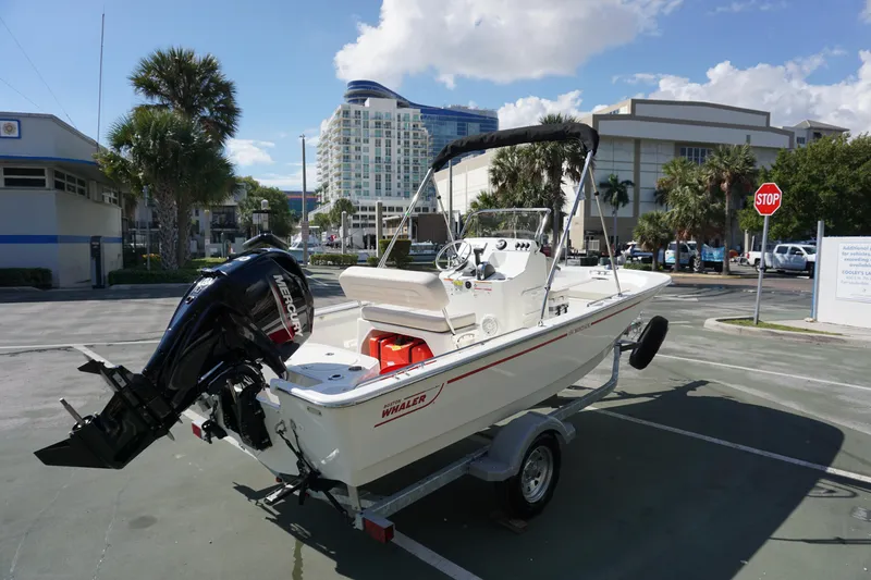 Slide: The Image of 2025 Boston Whaler 150 Montauk boat on trailer in urban setting. - 4