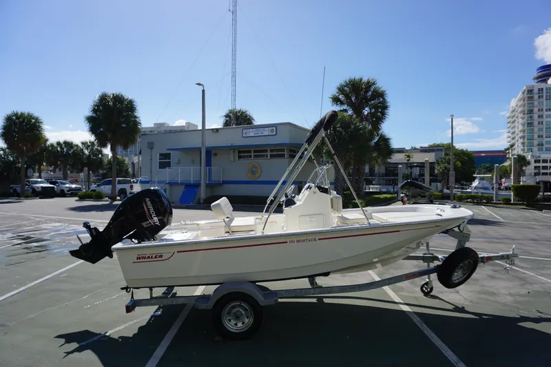 Slide: The Image of 2025 Boston Whaler 150 Montauk boat on trailer in sunny parking lot. - 5
