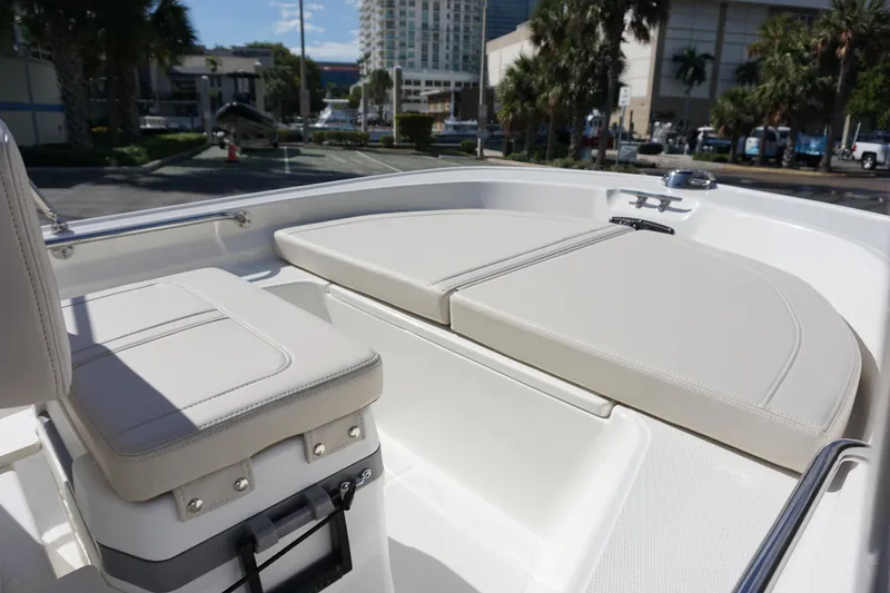 Slide: The Image of 2025 Boston Whaler 150 Montauk boat interior with cushioned seating in a marina setting. - 9