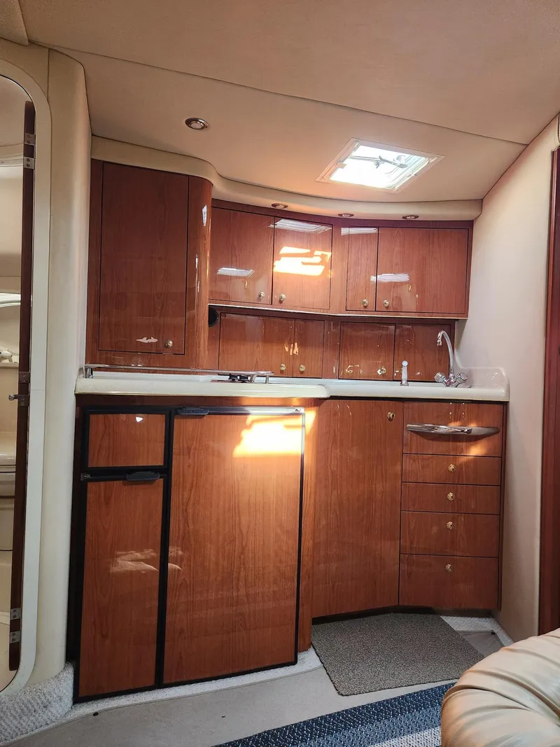 Slide: The Image of 2000 Sea Ray 370 Express Cruiser interior kitchen with wood cabinets and compact appliances. - 14