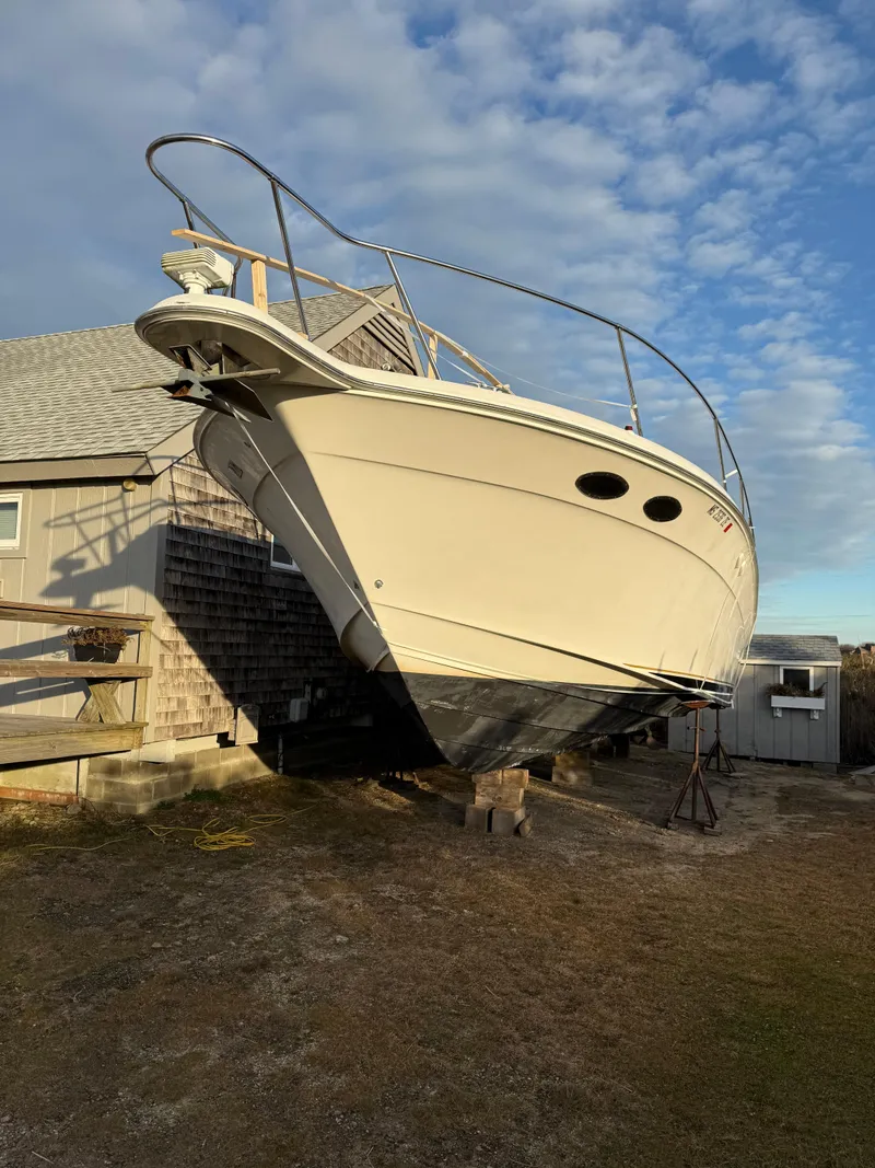 Slide: The Image of 2000 Sea Ray 370 Express Cruiser on dry dock beside a wooden building. - 3