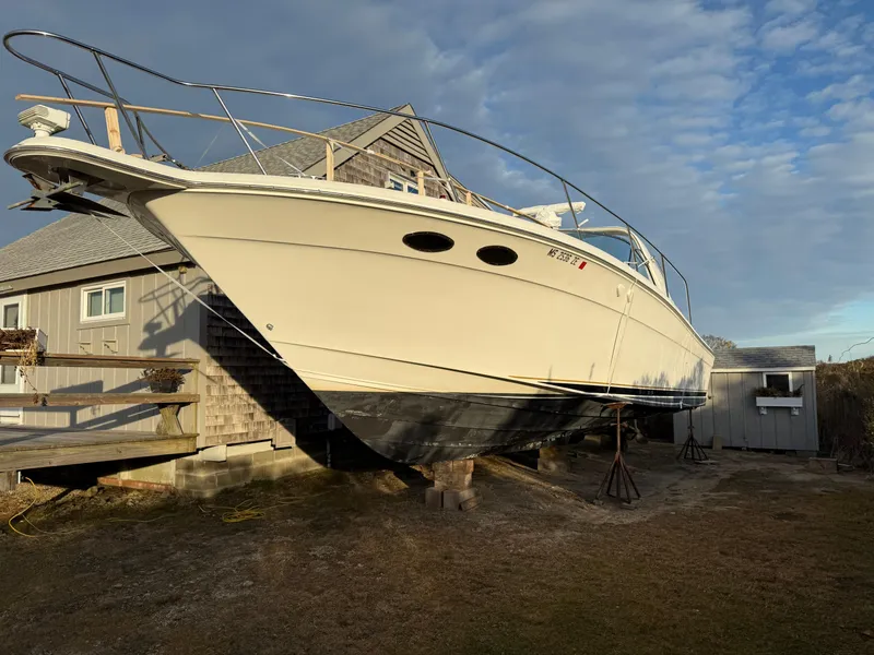 Slide: The Image of 2000 Sea Ray 370 Express Cruiser on dry dock near a house under a blue sky. - 4