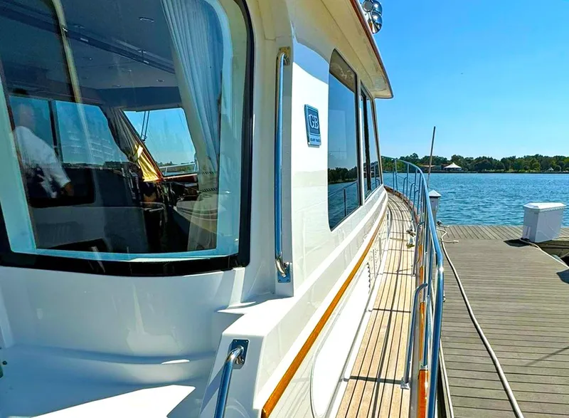 Slide: The Image of 2014 Grand Banks 46 Eastbay FB yacht docked by a serene waterfront. - 16