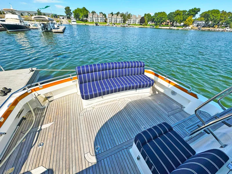 Slide: The Image of 2014 Grand Banks 46 Eastbay FB yacht with striped seating, docked by a scenic waterfront. - 17