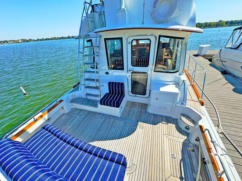 Slide: The Image of 2014 Grand Banks 46 Eastbay FB yacht with spacious deck and striped seating by the water. - 18