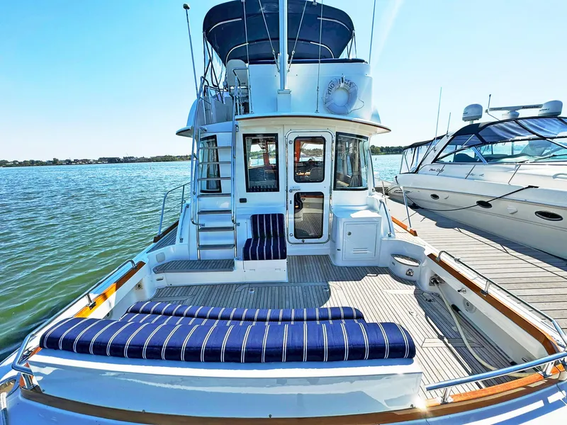 Slide: The Image of 2014 Grand Banks 46 Eastbay FB yacht with striped seating, docked by the water. - 19