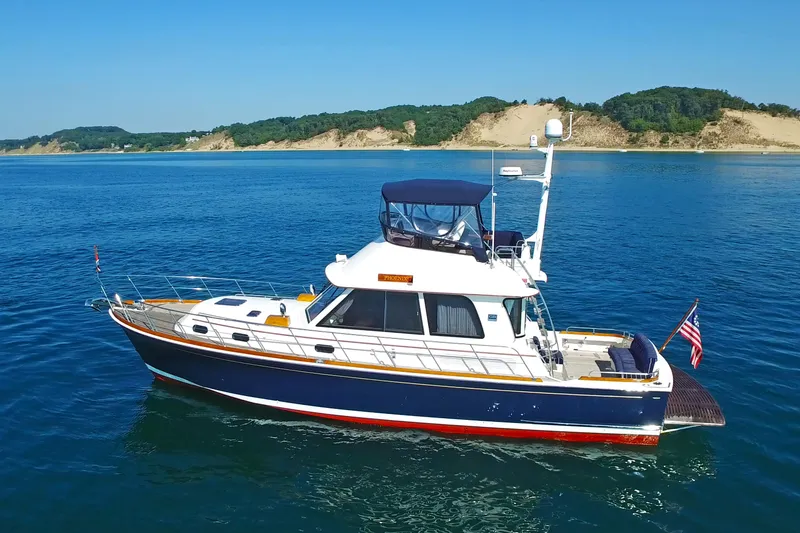 Slide: The Image of 2014 Grand Banks 46 Eastbay FB yacht on calm blue water, scenic coastline background. - 5