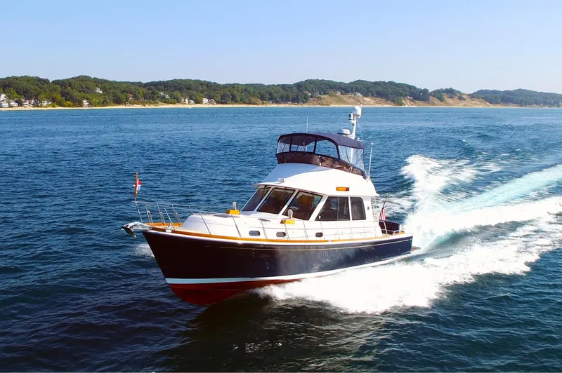 Slide: The Image of 2014 Grand Banks 46 Eastbay FB cruising on open water, scenic coastal background. - 6