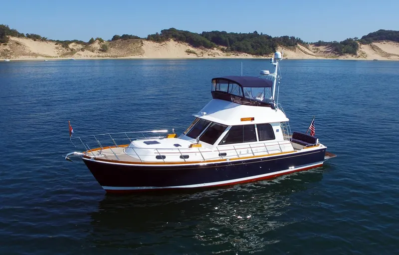 Slide: The Image of 2014 Grand Banks 46 Eastbay FB yacht cruising on calm waters near sandy shores. - 8