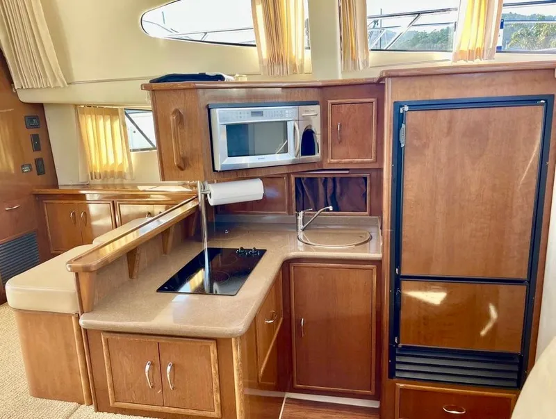 Slide: The Image of 2007 Carver 35 Super Sport yacht kitchen with wood cabinetry, microwave, and compact appliances. - 27