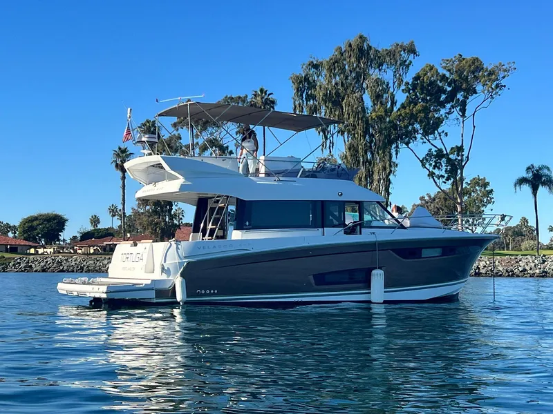 Slide: The Image of 2017 Jeanneau Velasco 43F yacht on calm water, surrounded by trees and clear blue sky. - 6