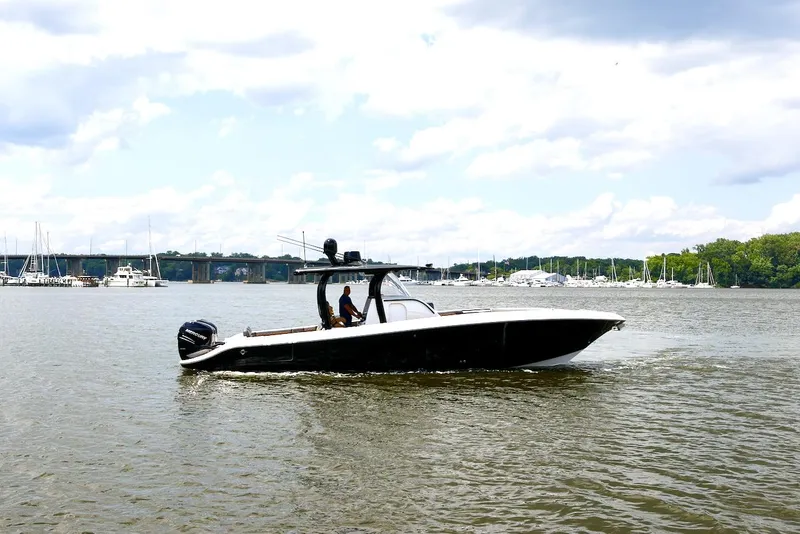 Slide: The Image of 2020 Fountain 39 NX boat cruising on a calm river under a cloudy sky. - 2