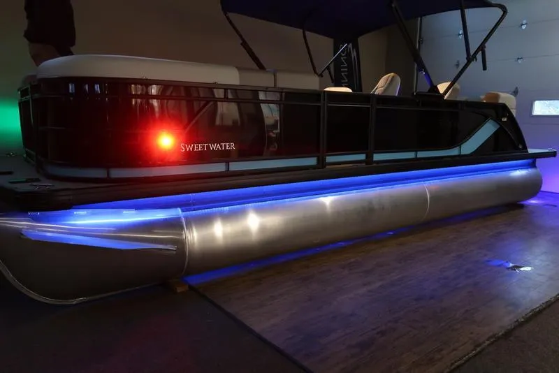 Slide: The Image of 2025 Sweetwater SW 2286 QS pontoon boat with blue LED lights in a showroom. - 24