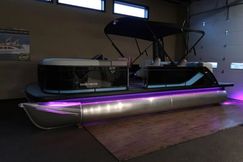 Slide: The Image of 2025 Sweetwater SW 2286 QS pontoon boat with purple LED lights in a showroom. - 26